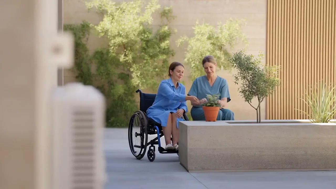 An illustrative scene of two adults enjoying a shared moment with a plant in a sunny courtyard.